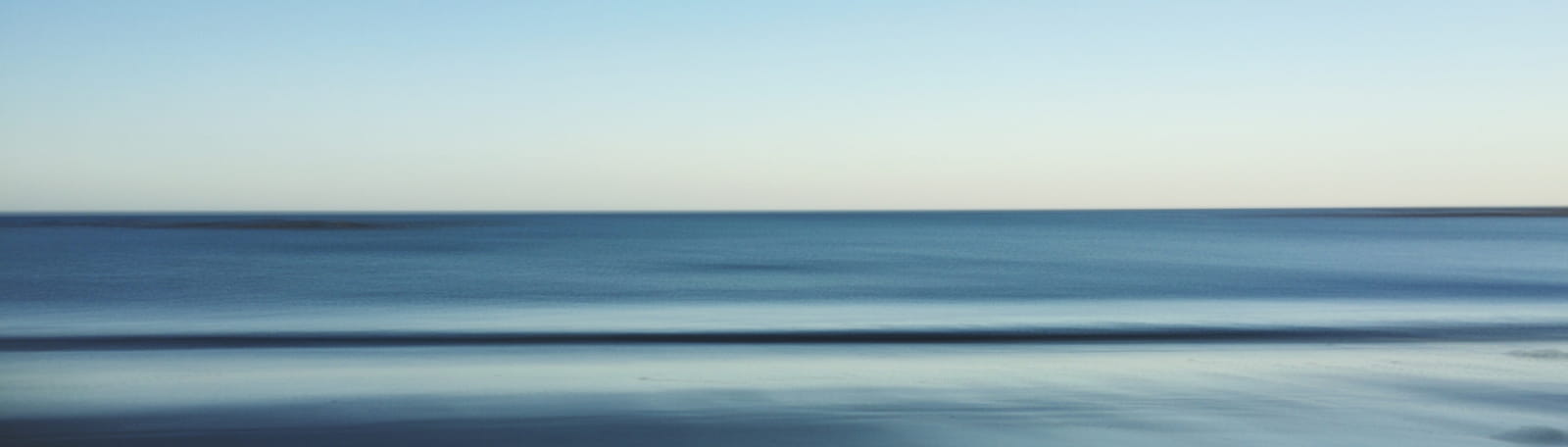 Hero image of the ocean meeting a blue horizon.