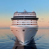 The front view of an MSC Cruises ship sailing through calm waters at sunset, symbolizing luxury travel and ocean exploration.