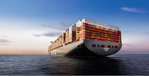 An MSC cargo ship loaded with colorful shipping containers sailing at sunset, highlighting MSC's global maritime shipping services.
