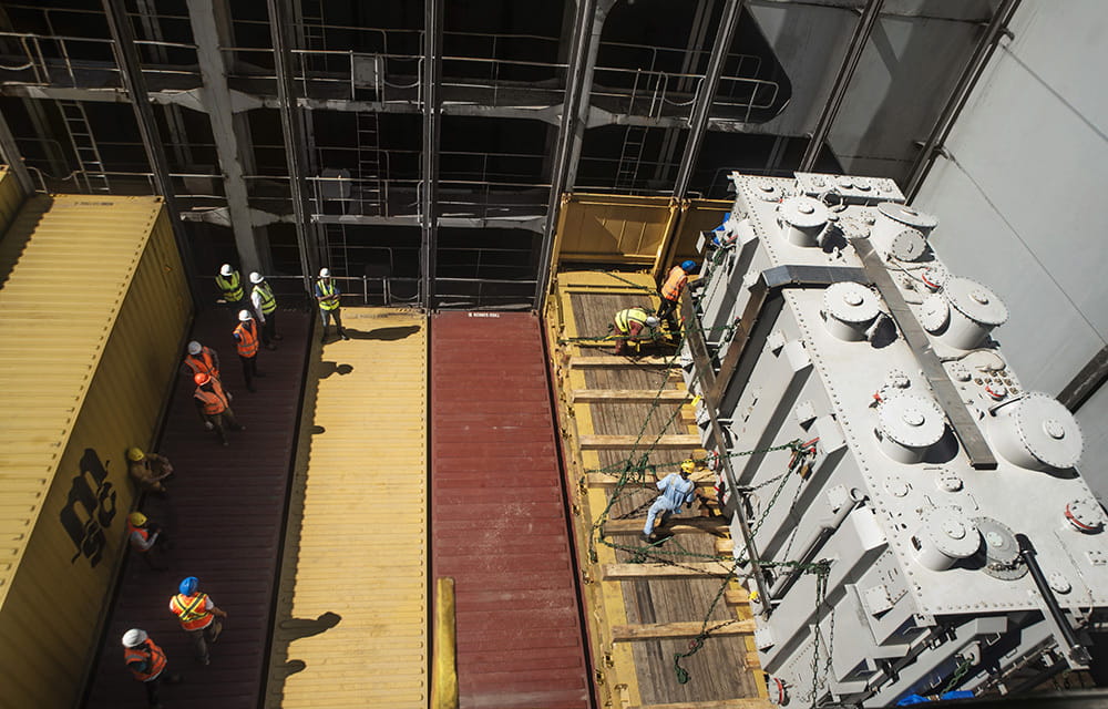 Several men are engaged in the transportation of a large transformer