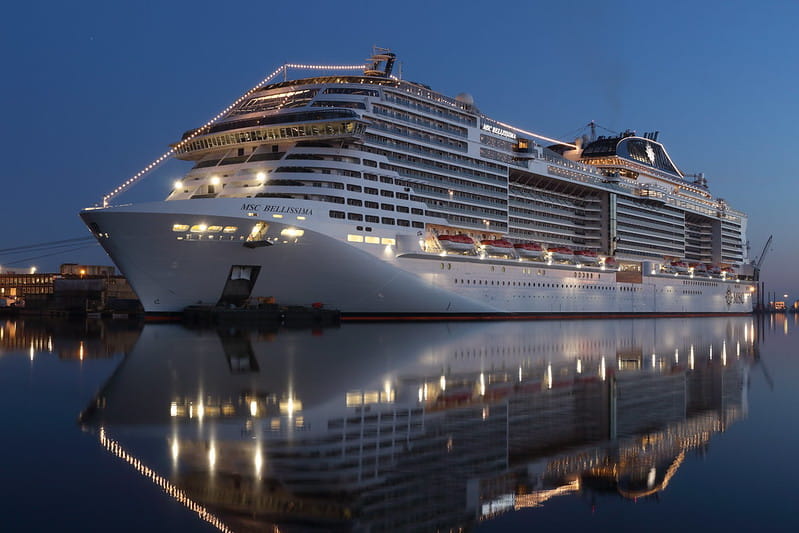 The MSC Cruises ship “MSC Bellissima” docked at the port at night, embellished with lights.